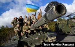 Украинские военнослужащие позируют на танке Challenger 2 на военной базе Bovington Camp на юго-западе Великобритании, где проходят обучение, 22 февраля 2023 года