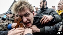 Ukarine -- An alleged sniper and member of the pro-government forces is beaten by anti-government protesters in Kiev today.