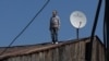 A Georgian man looks on after checking a satellite dish on the roof of a building in Tbilisi in April.