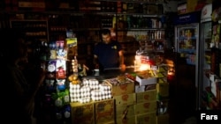 An Iranian shopkeeper works in the dark after a mass outage in the capital, Tehran. (file photo)